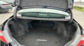 Open trunk of a black Toyota Camry showing a spacious cargo area with a ribbed mat and gray lining, in a dealership lot.