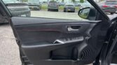 View from inside a car door, looking out at a dealership parking lot with several parked SUVs and sedans.