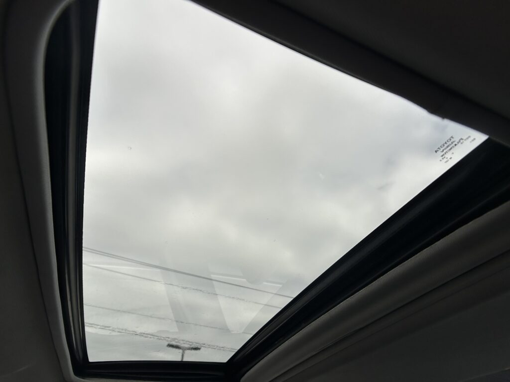 Panoramic sunroof viewed from inside a car, showing a cloudy sky through the glass panels