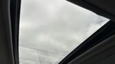Panoramic sunroof viewed from inside a car, showing a cloudy sky through the glass panels
