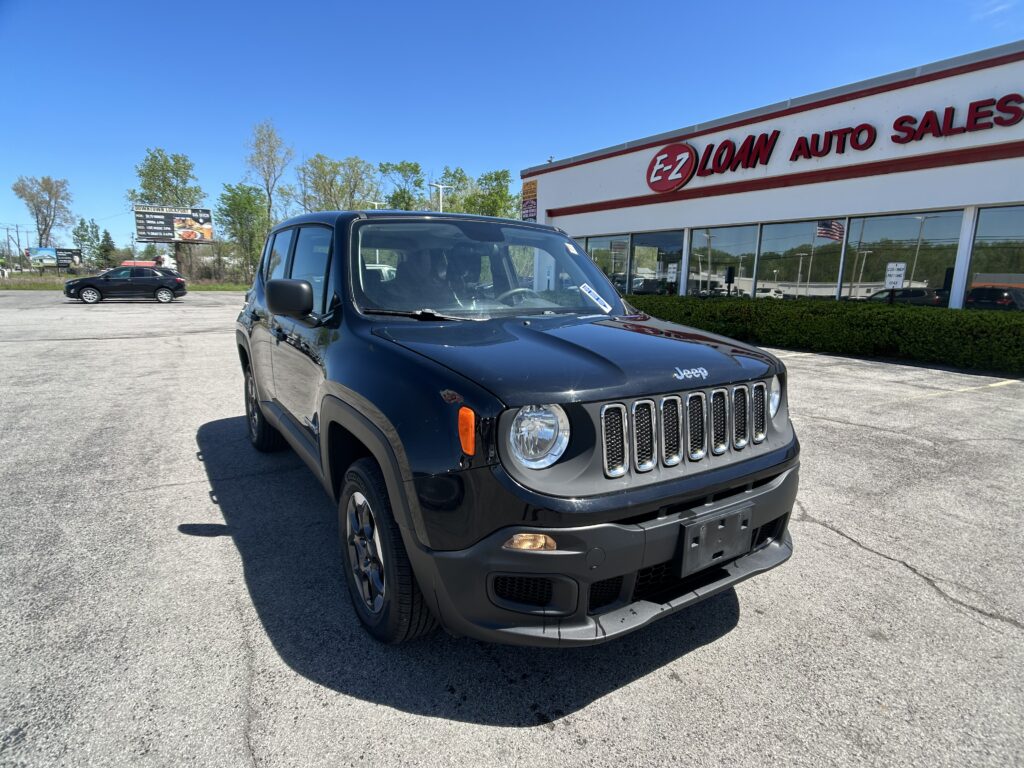 Black Jeep SUV parked in front of a red-and-white E-Z LOAN Auto Sales storefront on a sunny day.