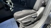 Interior view of a dark car showing the front seats, center console with gear shift, and a sheet of paper on the floor near the driver's side; seat belt and fabric upholstery visible.