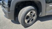 Close-up of a vehicle's front wheel and fender, showing the tire and suspension inside the wheel well on a dark SUV/minivan.