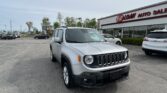 Silver Jeep in the foreground at a used car dealership, EZ Loan Auto Sales, with several cars in the lot.