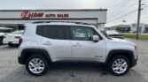 White SUV parked at a car dealership with 'EZ LOAN AUTO SALES' sign on the building in the background
