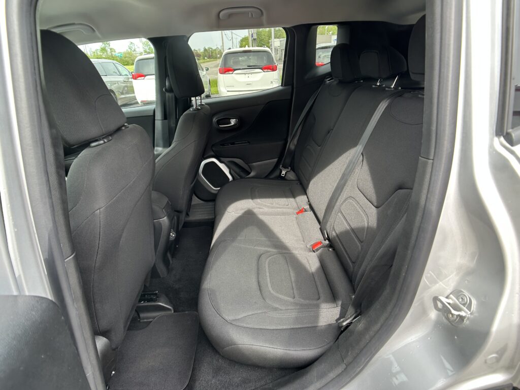 Interior of a car with black fabric backseat and headrests, viewed from the open rear door