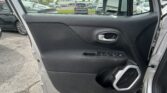 Driver's-side car door interior with window controls and handle; parking lot and dealership buildings visible outside