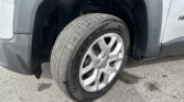 Front wheel and tire of a gray van, showing alloy rim and tread details near the wheel well