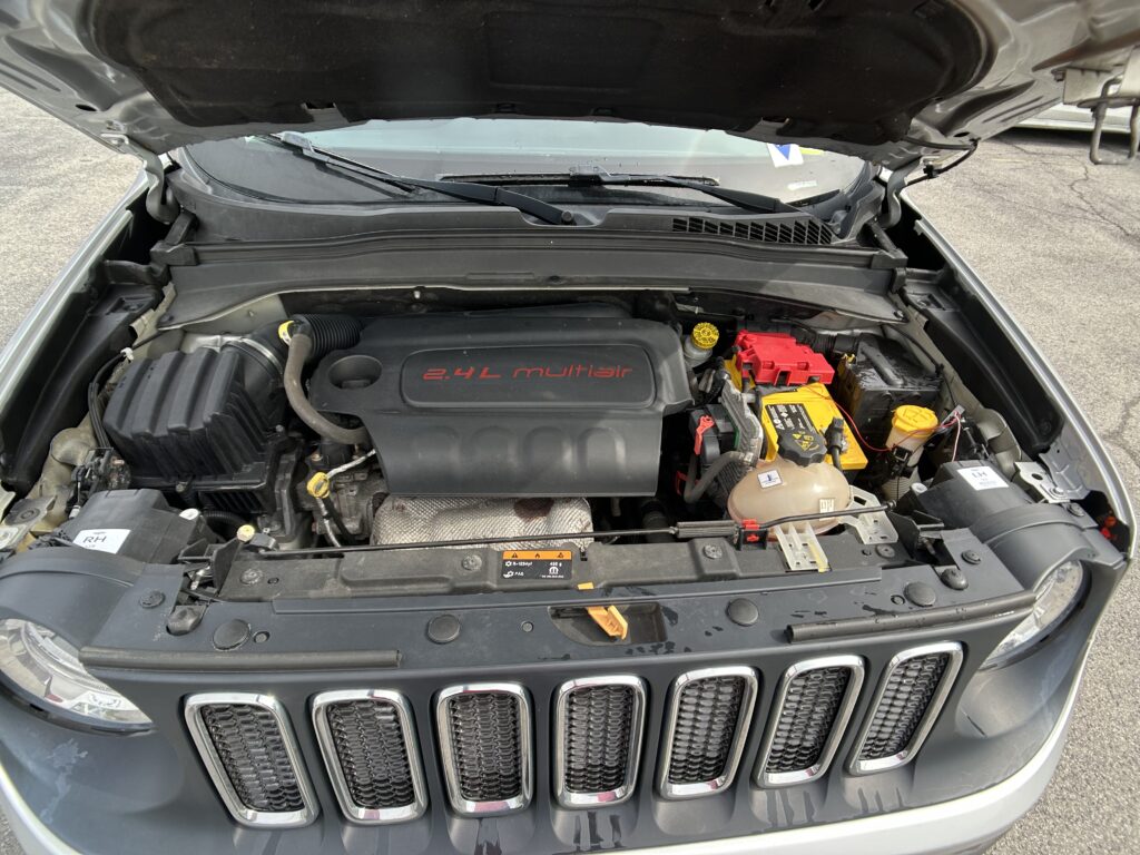 Engine bay with open hood; shows 2.4L MultiAir engine and battery on the passenger side near the grille