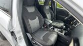 Front interior of a car with two dark fabric seats, center console, and door open on the driver's side.