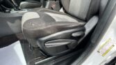 Interior of a car showing front seats, center console with gear shifter, and door frame with a warning label badge nearby.