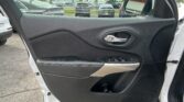 Car door interior with power window controls and chrome latch; outside parking lot visible through the window and mirror.