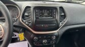 Interior of a car from the driver's seat showing the instrument cluster, center touchscreen, gear shifter, and climate controls including knobs and buttons.