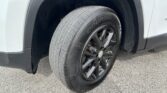 Close-up of a car tire and black alloy wheel in the front wheel well of a white vehicle.