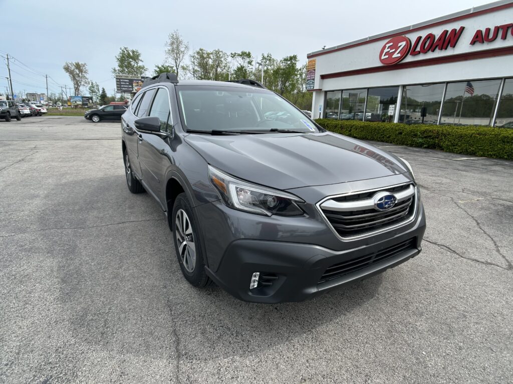 Silver Subaru SUV in a dealership lot, with an E-Z LOAN storefront in the background.