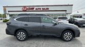 Gray Subaru Outback SUV in a dealership lot, with EZ Loan Auto Sales sign and other cars in the background.