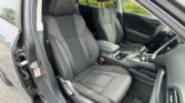Front interior of a car with black fabric seats, center console, and steering wheel visible from the open door.