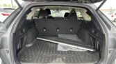 Open SUV trunk with rear seats upright, showing a spacious cargo area and a long metal rod lying on the floor mat.