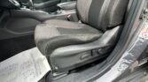 Interior of a car showing the front passenger seat, center console with cup holder and gear shifter, and partial steering wheel on the left side at the door frame. A paper floor mat is visible.