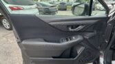 Driver-side car door interior with control panel and window buttons; outside parking lot with multiple cars visible in the distance and a side mirror in view.