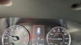 Dashboard view from the driver: left tachometer, right speedometer, central digital display showing a car icon with red outline and door alert.