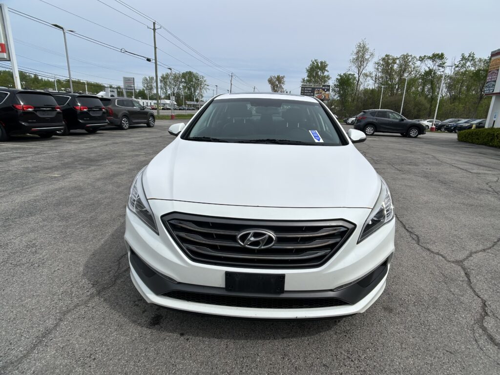 Front view of a white Hyundai SUV parked in a busy parking lot with other vehicles nearby on an overcast day