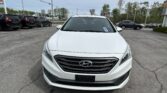 Front view of a white Hyundai SUV parked in a busy parking lot with other vehicles nearby on an overcast day