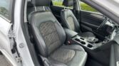 Interior of a car showing black leather front seats, center console, and dashboard with the driver’s door open to the outside.