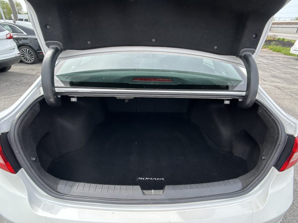 Open trunk of a white Hyundai Sonata, showing a spacious black cargo area and rear window.