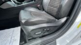 Interior of a car showing the front seats, center console, and gear shifter; black leather upholstery and a red seatbelt buckle visible on the side of the driver seat.