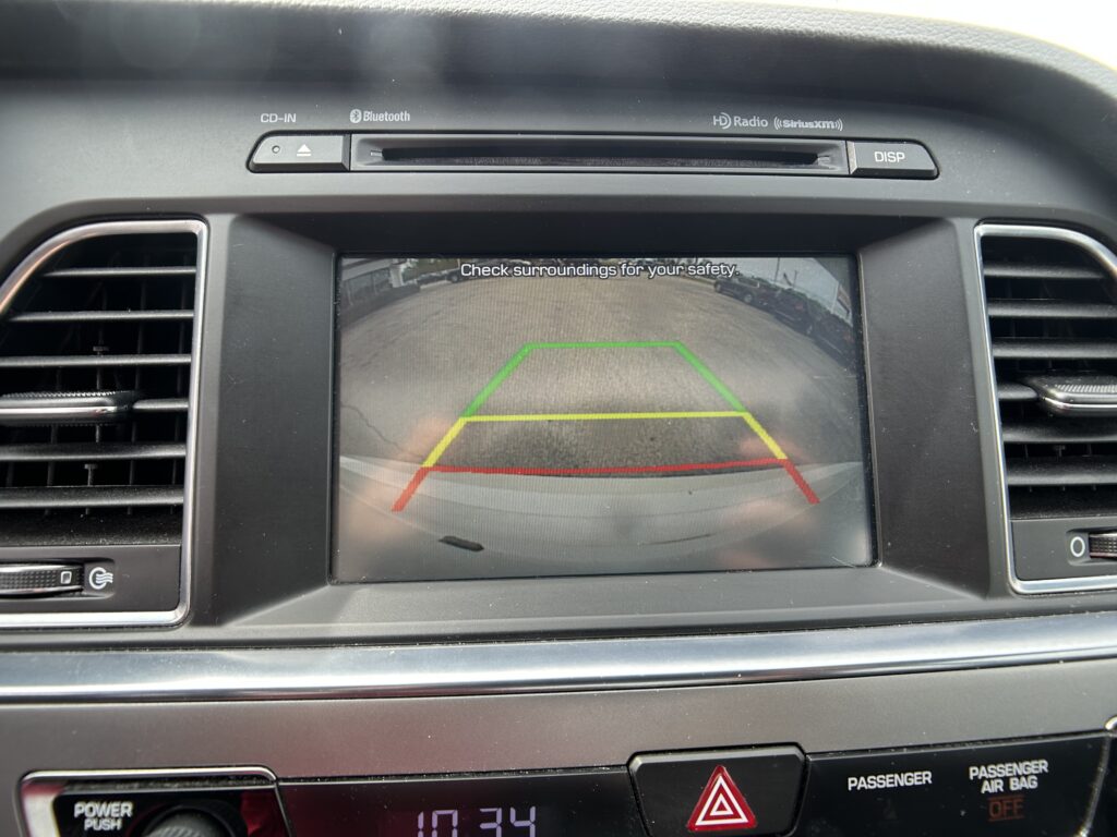 Rearview camera display on car dash with colored parking guide lines (green, yellow, red).