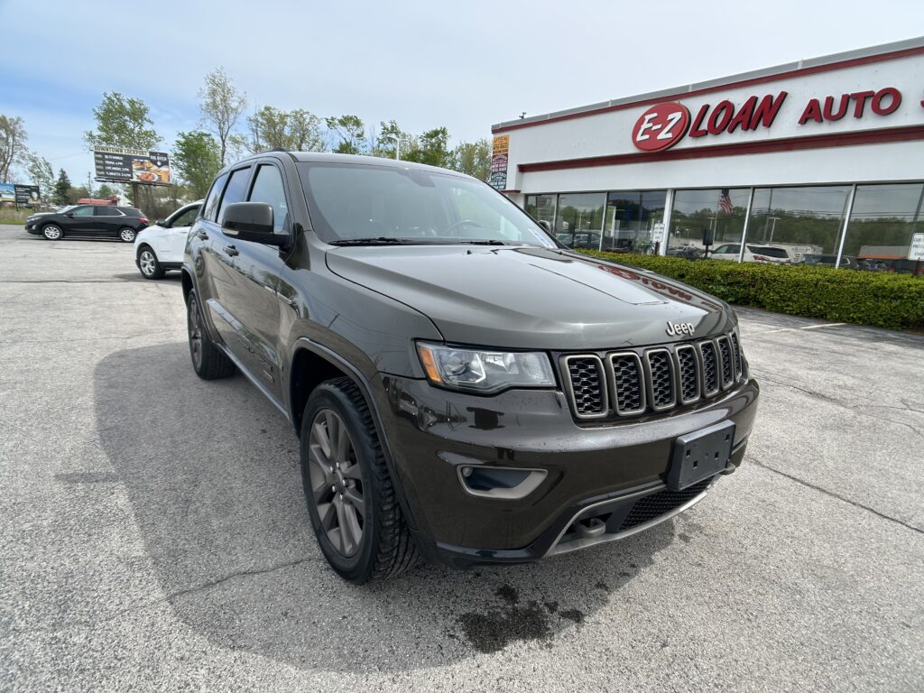 Dark gray Jeep SUV parked in a dealership lot with the E-Z LOAN AUTO storefront in the background.