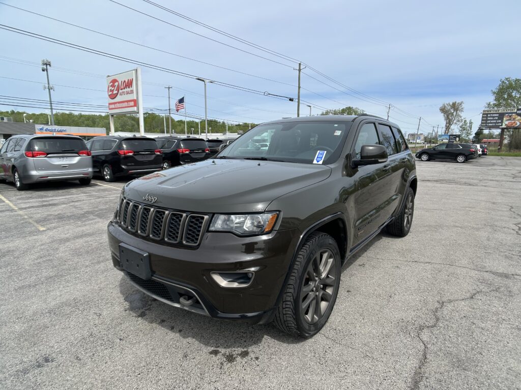 Gray Jeep SUV in the foreground at a car dealership lot, with a row of vehicles and an EZ Loan Auto Sales sign in the background.