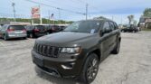 Gray Jeep SUV in the foreground at a car dealership lot, with a row of vehicles and an EZ Loan Auto Sales sign in the background.