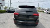 Rear view of a dark gray Jeep SUV in a parking lot, with power lines overhead and other cars in the background.