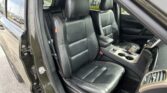 Open front door view of a dark SUV interior with black leather seats and red stitching, center console visible.