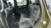Rear passenger seats in a black leather SUV with headrests; outside traffic visible through windows.