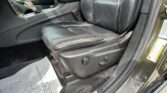 Driver's black leather seat with red contrast stitching, center console, and gear shifter visible in a car interior