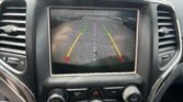 In-dash display shows a rearview camera view with green, yellow, and red guide lines for parking, and the message 'Check Entire Surroundings' at the top of the screen.