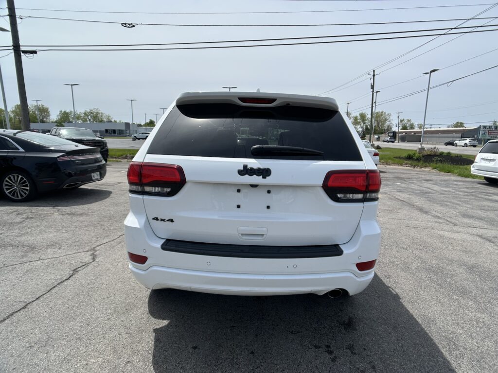Rear view of a white Jeep SUV parked in a lot, showing the tailgate, rear window, and 4x4 badge