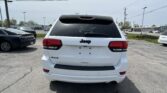 Rear view of a white Jeep SUV parked in a lot, showing the tailgate, rear window, and 4x4 badge
