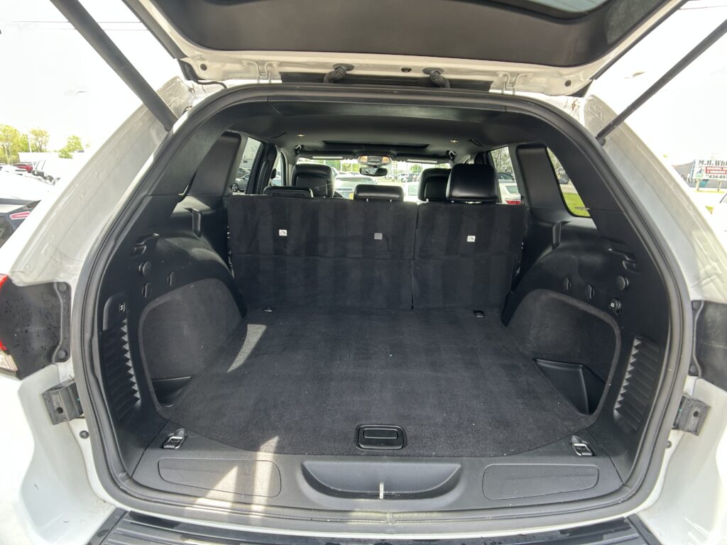 Open SUV trunk with rear seats upright and spacious cargo area visible in a parking lot.