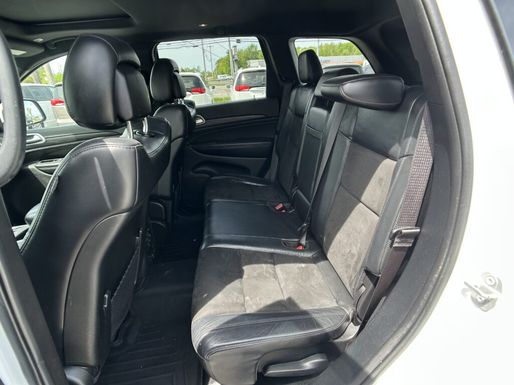 Black leather rear seating area of an SUV, with bench and folded headrests visible from the open rear door