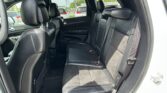 Black leather rear seating area of an SUV, with bench and folded headrests visible from the open rear door