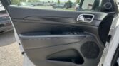 Interior view of a car door panel with a chrome handle and window controls, overlooking a parking lot through the open door