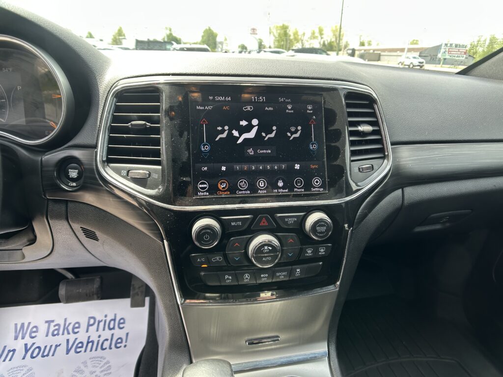 Center touchscreen climate control panel on a car dashboard with air vents and control knobs nearby