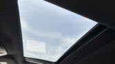 Interior of a car with an open sunroof showing a cloudy sky above.