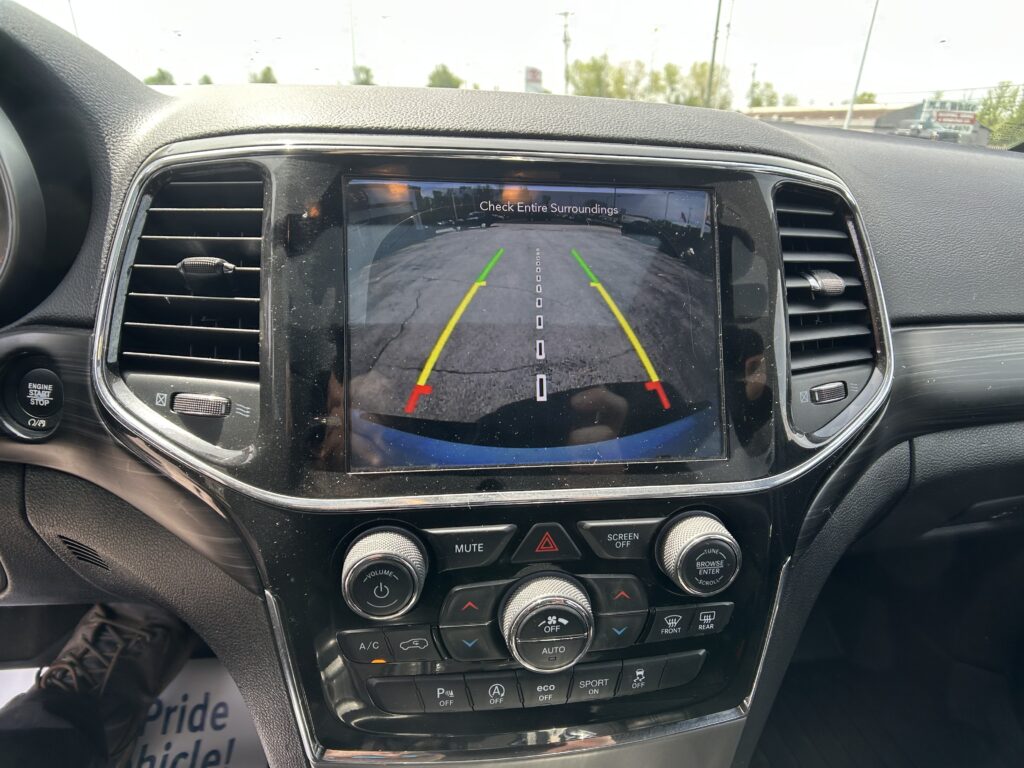 Infotainment screen showing rearview camera with green/yellow/red guide lines and 'Check Entire Surroundings' message