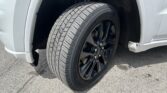 Close-up of a car tire on a black alloy wheel, with the silver vehicle’s wheel well visible behind it.