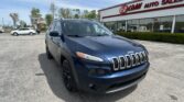 Blue Jeep SUV parked in the foreground of a car lot with a storefront that reads EZ Loan Auto Sales in the background.